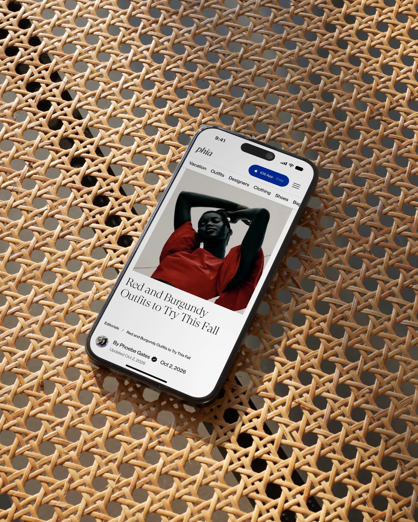 Phoebe Gates' editorial, Red and burgundy outfits to try this fall, on a phone lying on a cane chair