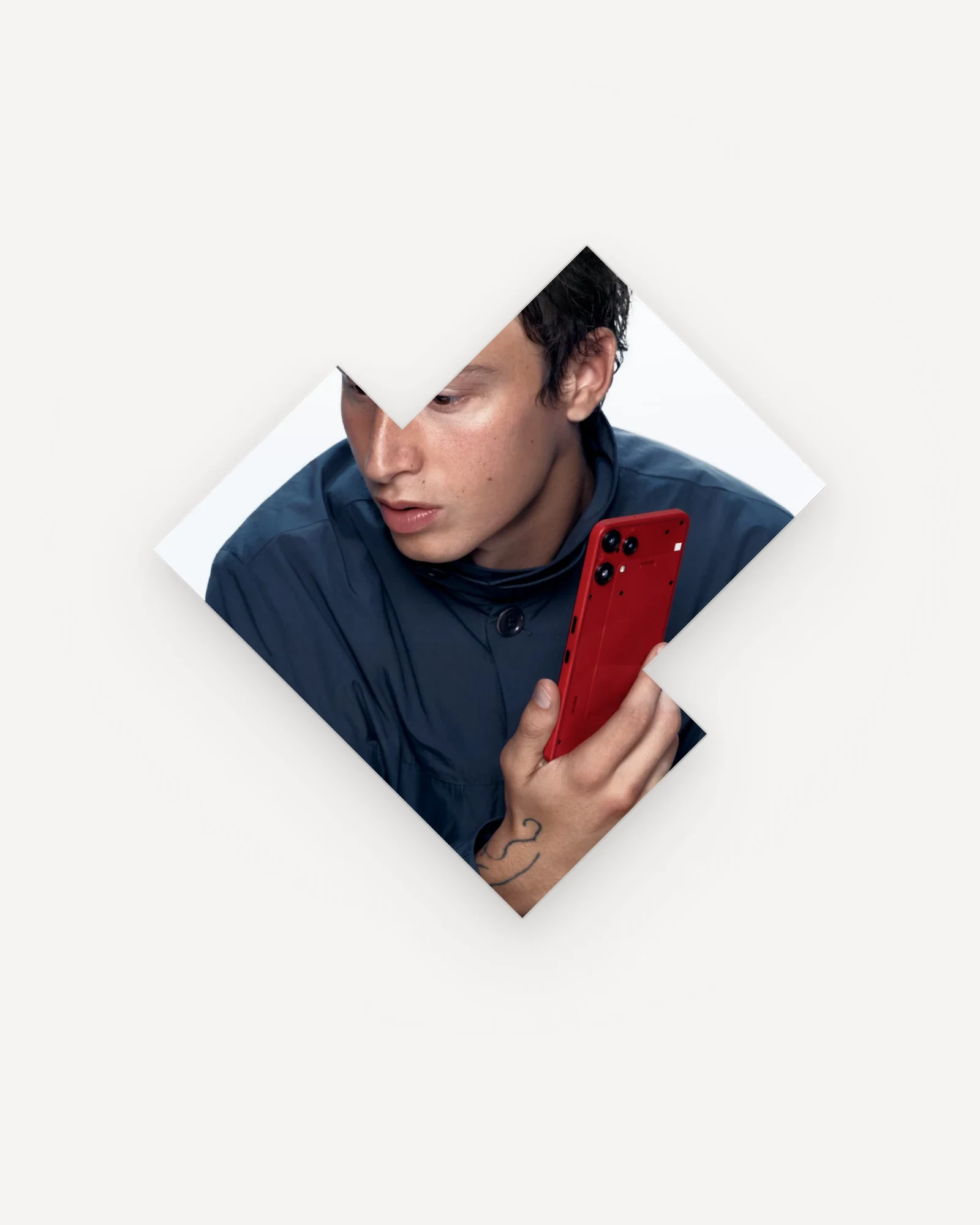 One block of the homepage strip on its own, cut to its real notched 45° outline: a young man in a navy jacket holding a red phone