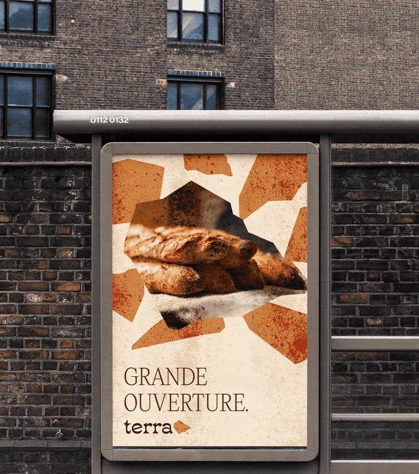 A Terra bus-shelter poster on a brick wall: baguettes framed by terracotta shards, GRANDE OUVERTURE. and the logo