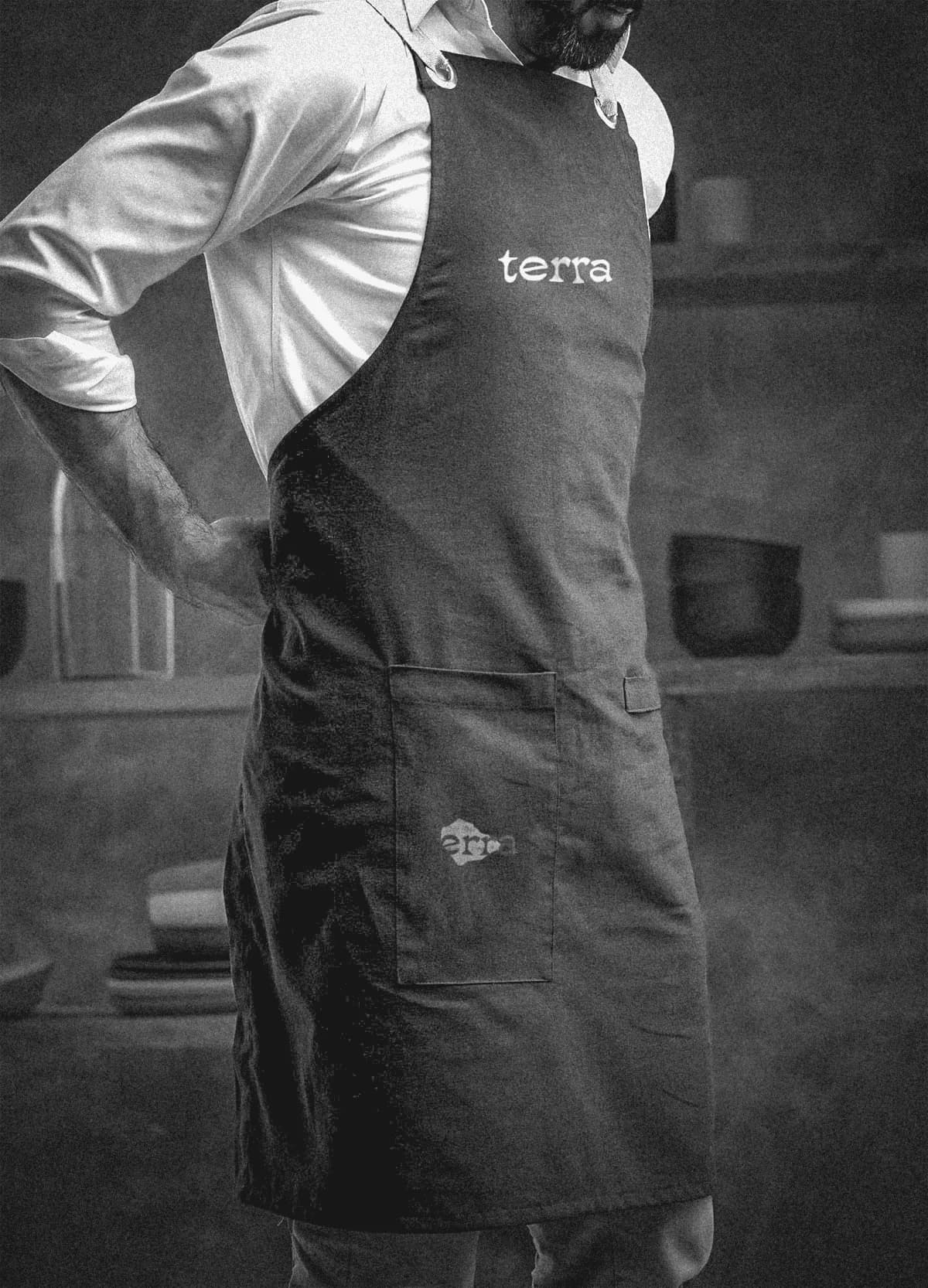 A black-and-white photo of a baker in a dark apron printed with terra