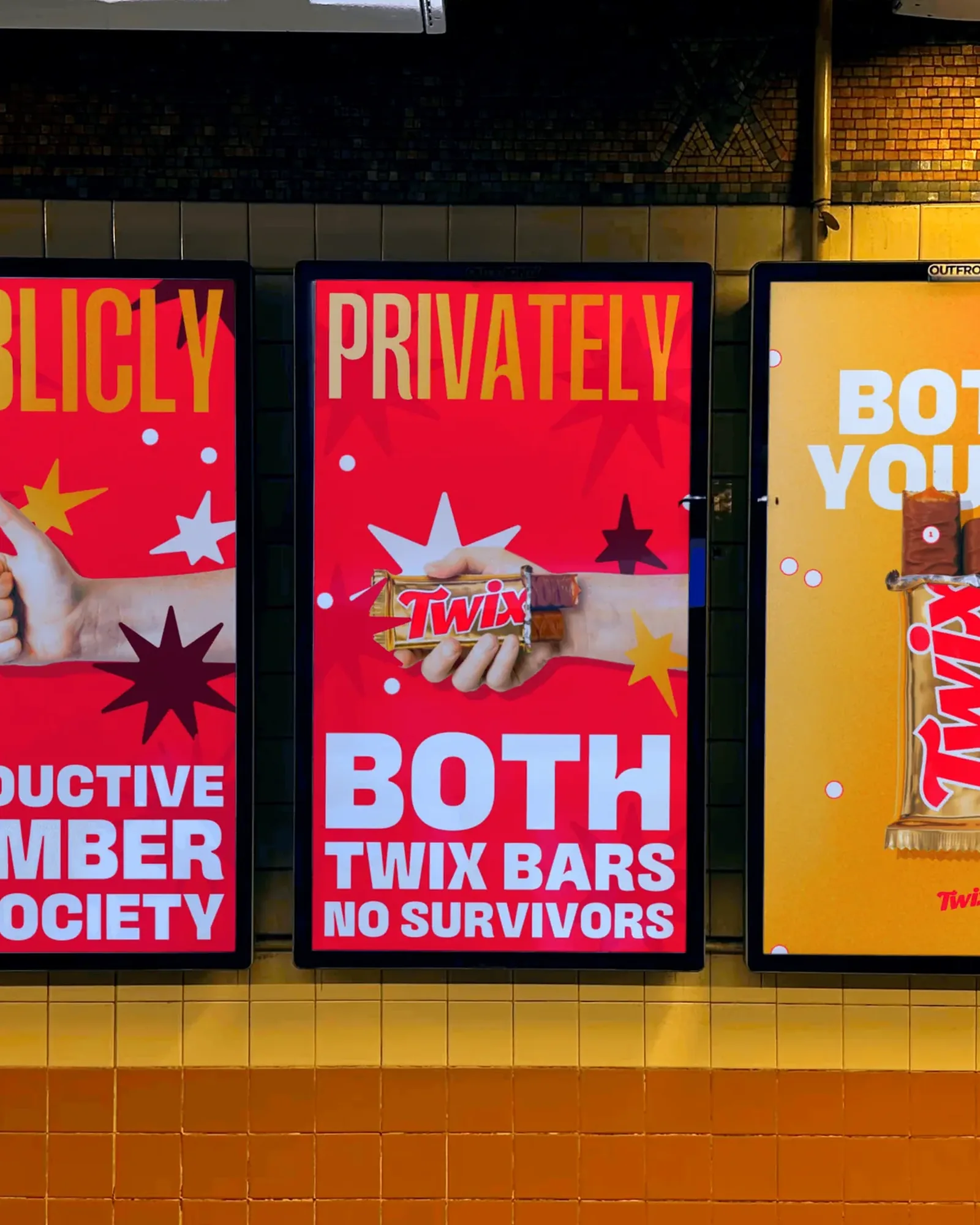 Three digital subway screens on yellow tile: PUBLICLY PRODUCTIVE MEMBER OF SOCIETY, PRIVATELY BOTH TWIX BARS NO SURVIVORS, and BOTH YOURS