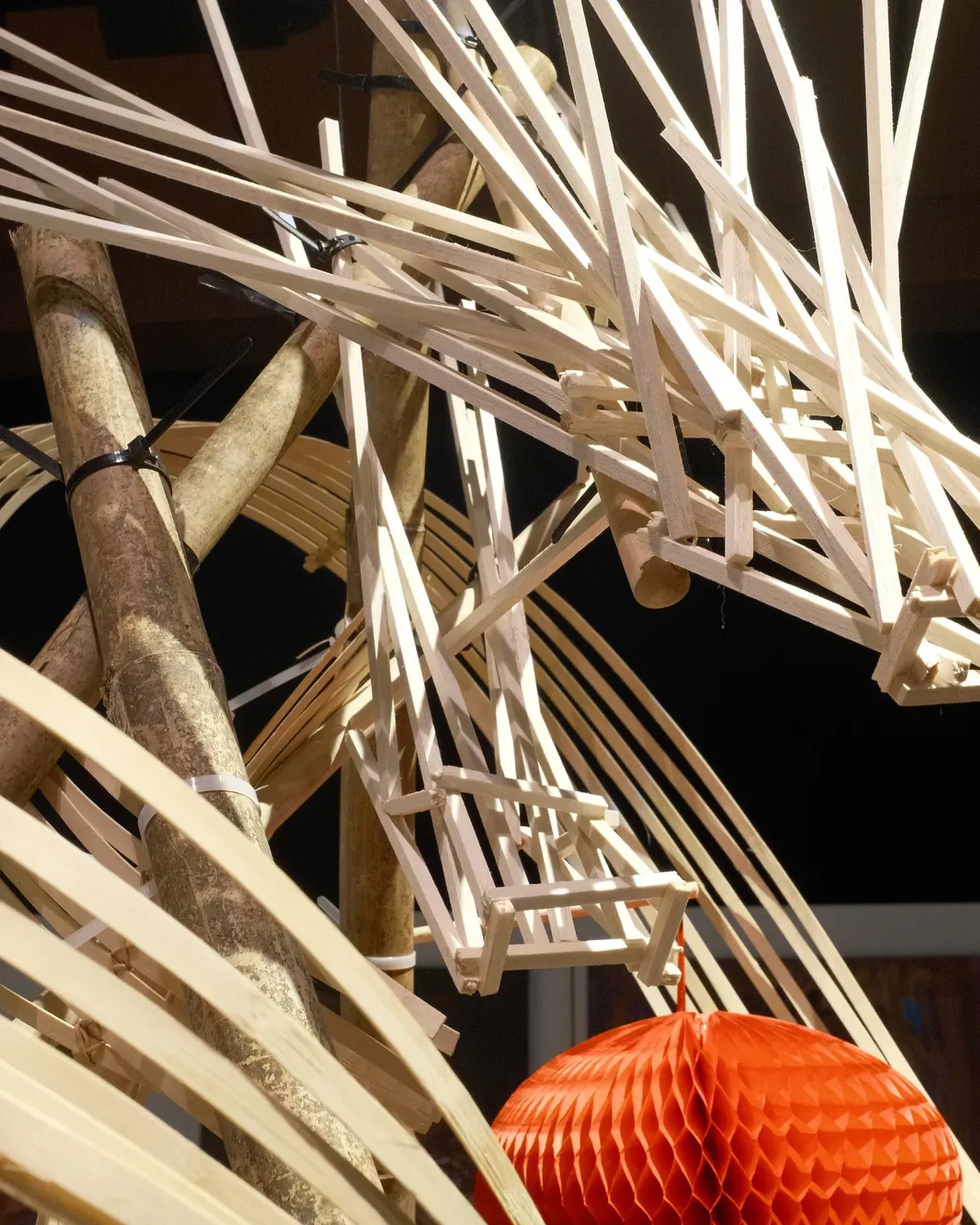 The bamboo dragon's head in close-up, strips of bamboo over a red lantern