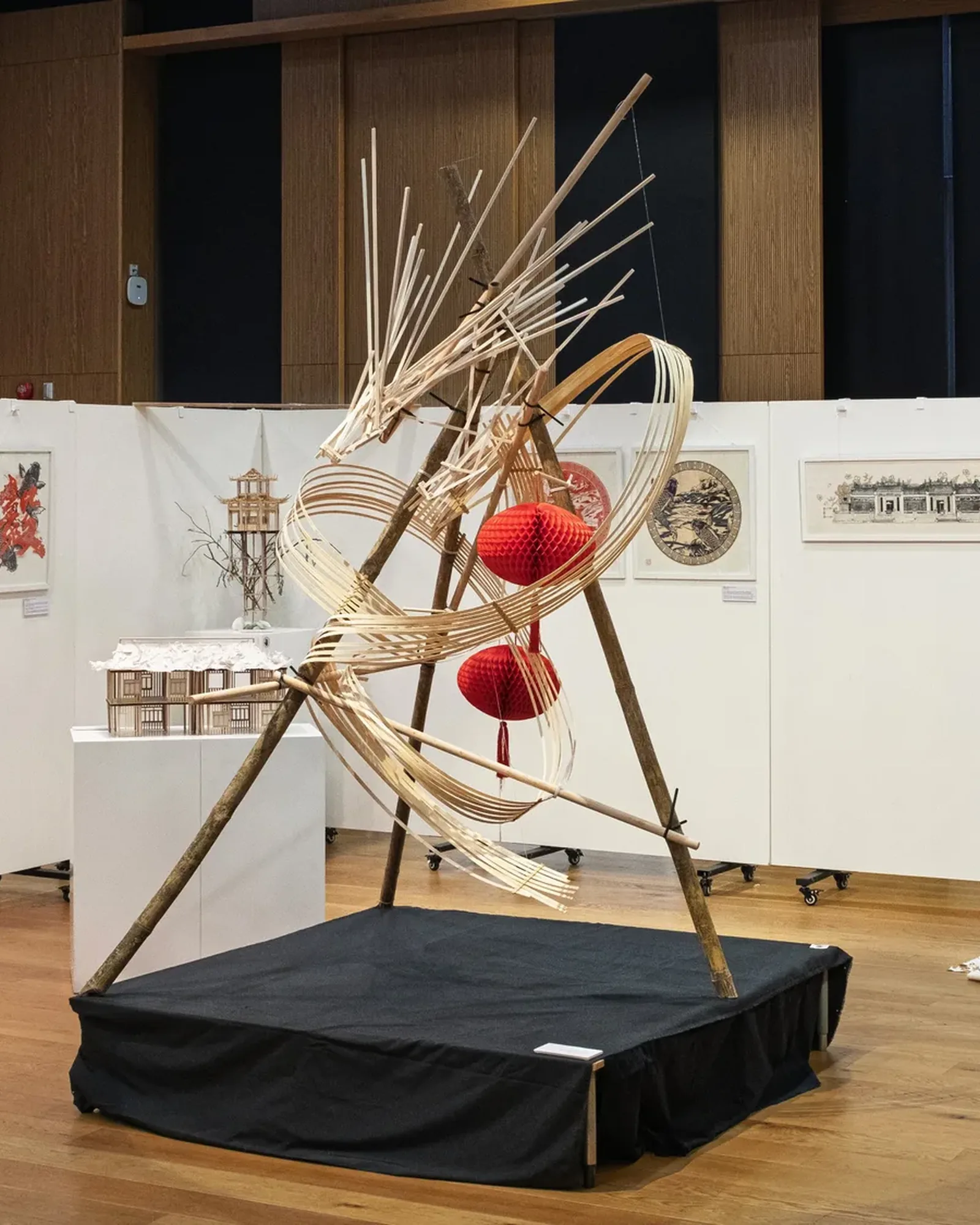 The Metamorphosis exhibition: the bamboo dragon on a black plinth, framed papercuts on white walls and a paper installation behind