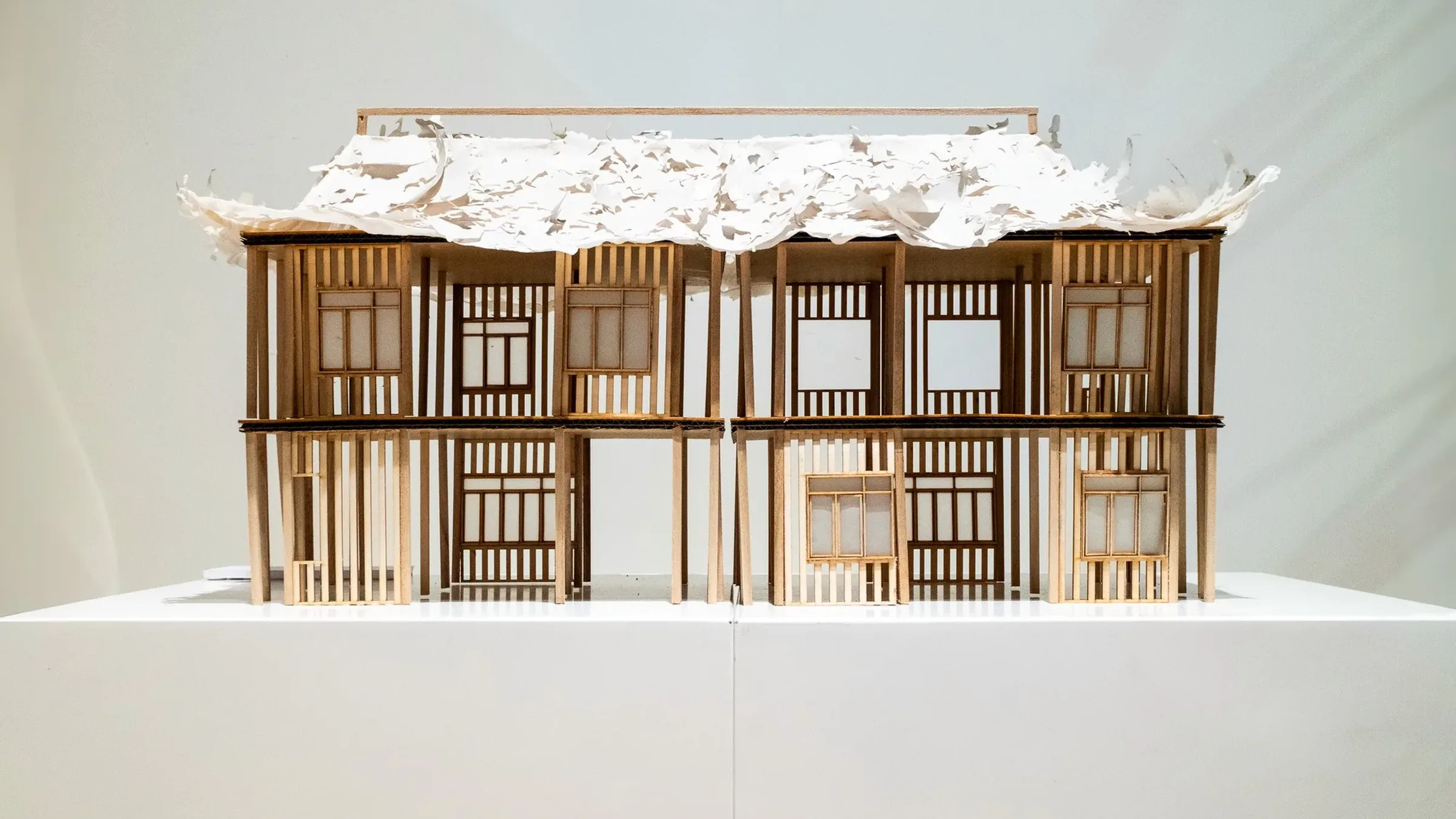 檐下 Under the Eaves, September 2024, balsa, newsprint and crepe paper, 20 × 56 cm: two storeys of shophouse fronts under a torn paper roof